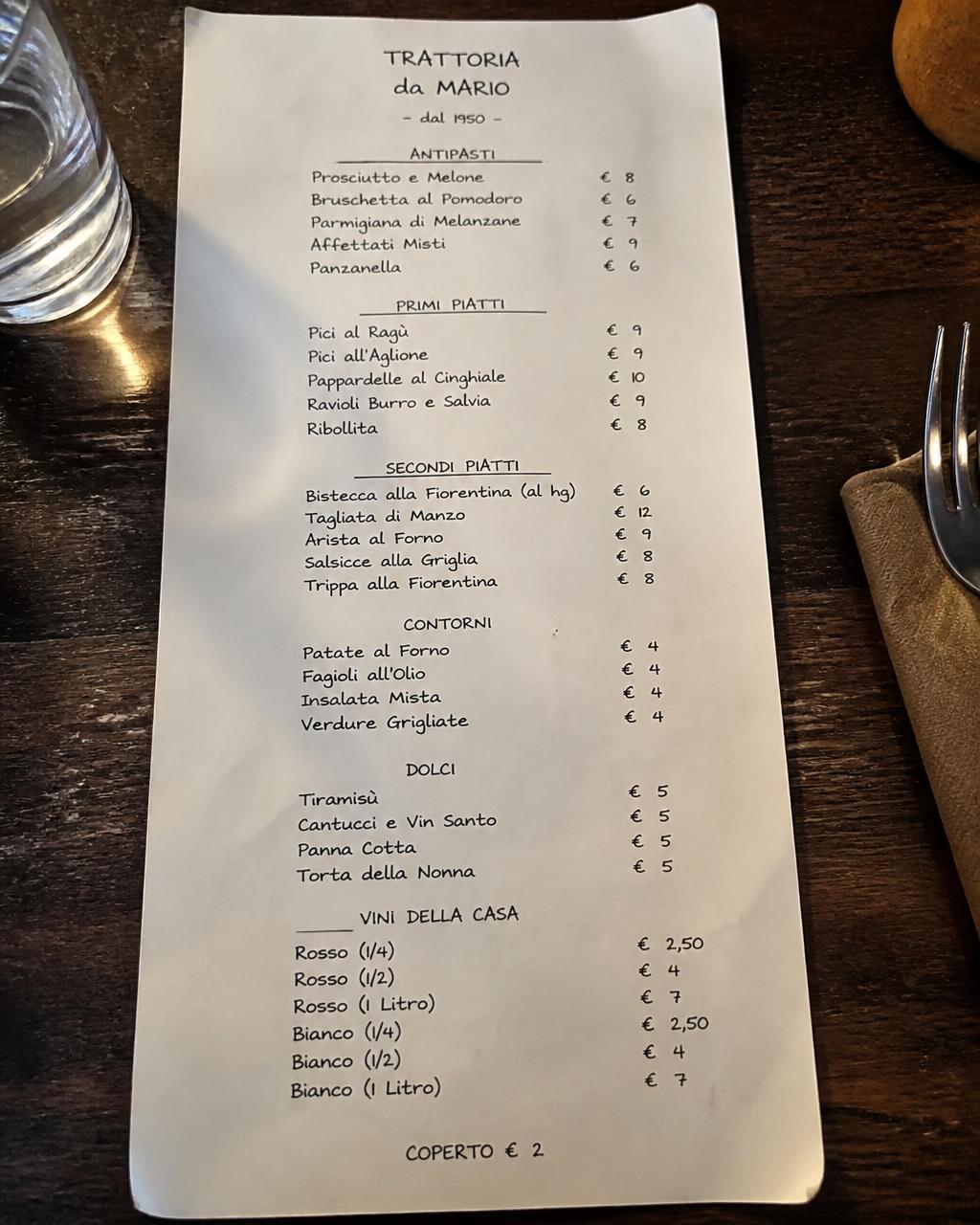 Menu cartaceo di una trattoria italiana appoggiato su un tavolo di legno